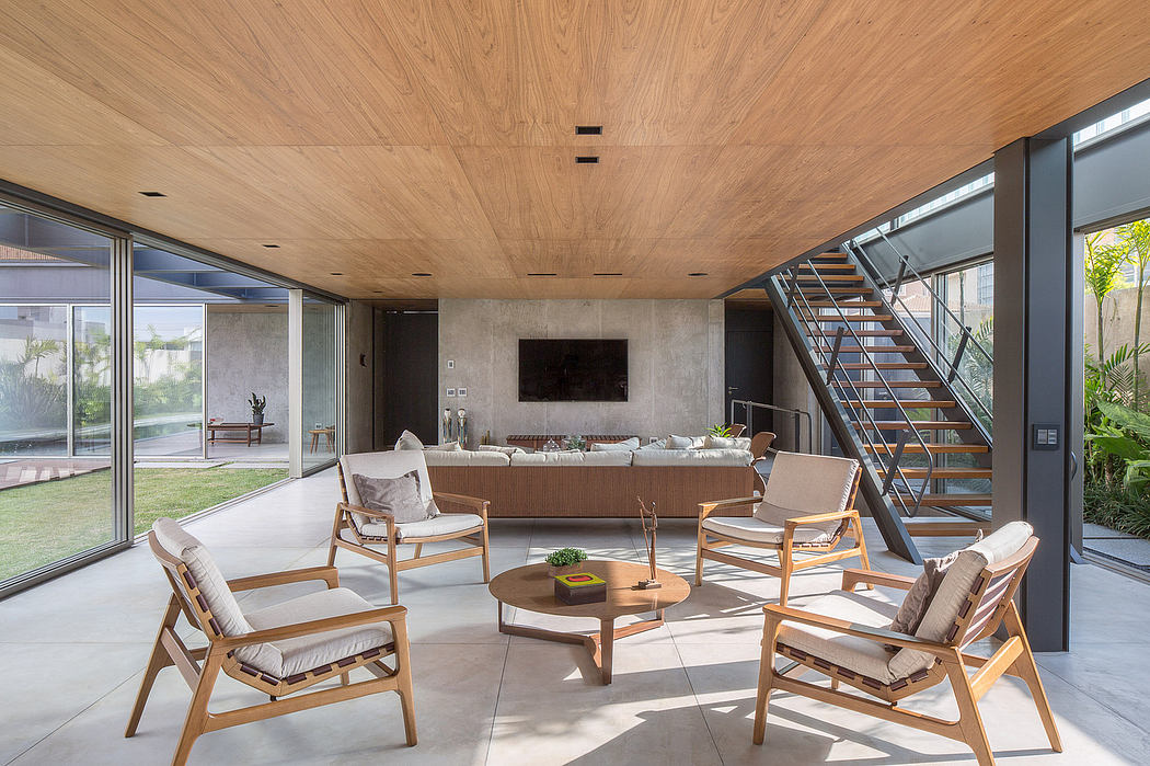 Spacious, open-plan living area with wood-paneled ceiling, glass walls, and modern furniture.