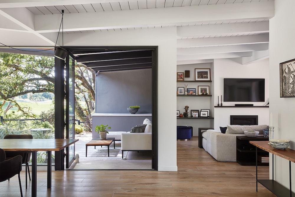 Modern, open-concept interior with high ceilings, exposed beams, and a mix of natural wood and black accents.