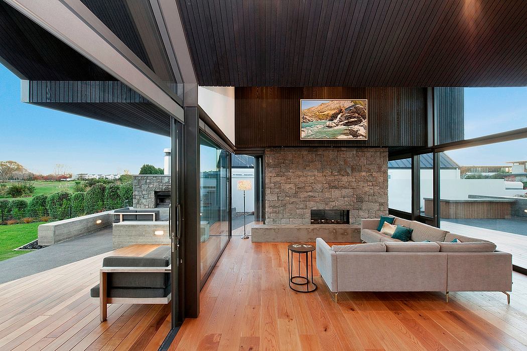 Contemporary living room with a stone fireplace, large glass doors, and wooden flooring.