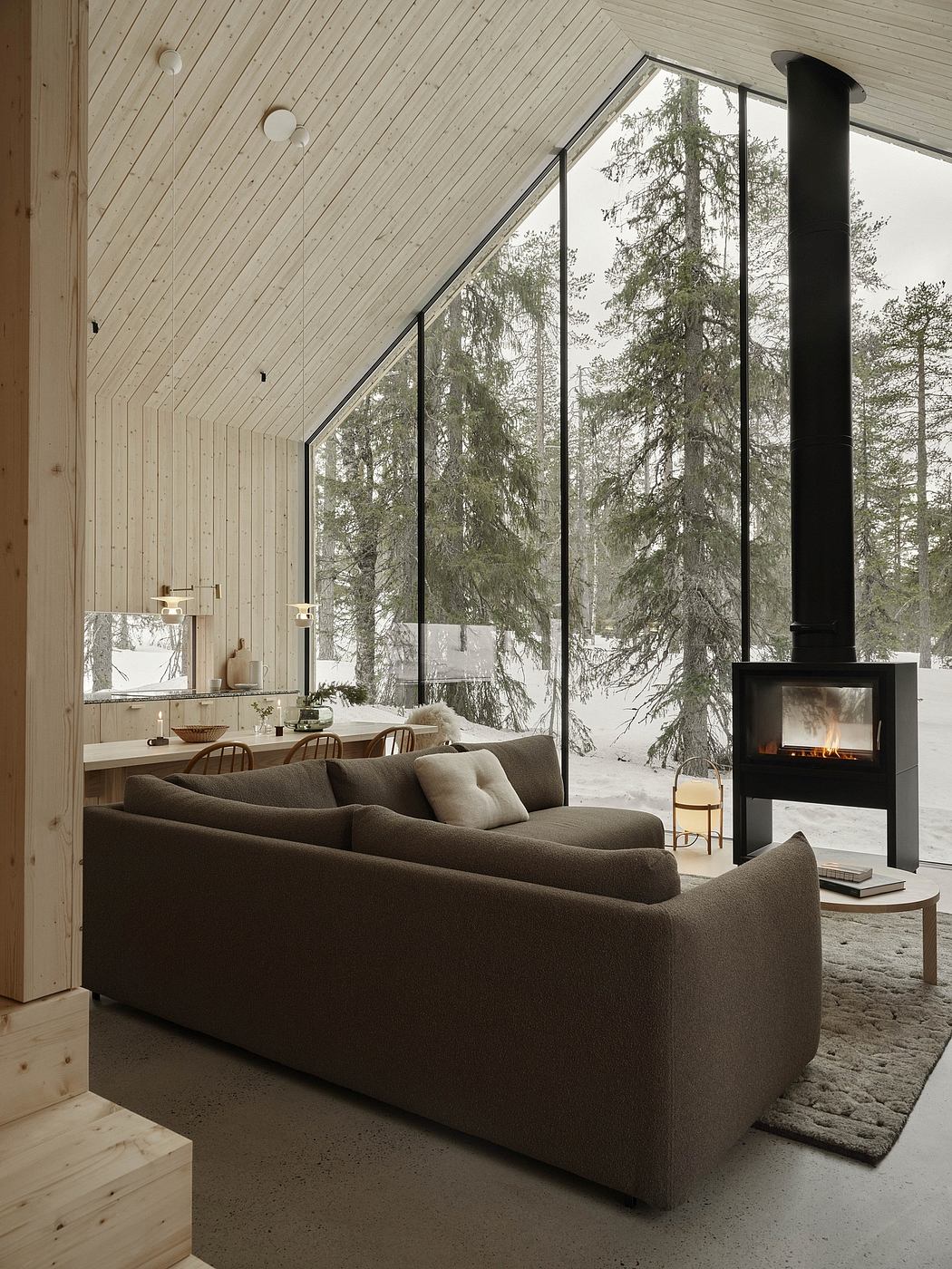 Cozy cabin interior with panoramic windows, fireplace, and wooden furnishings.