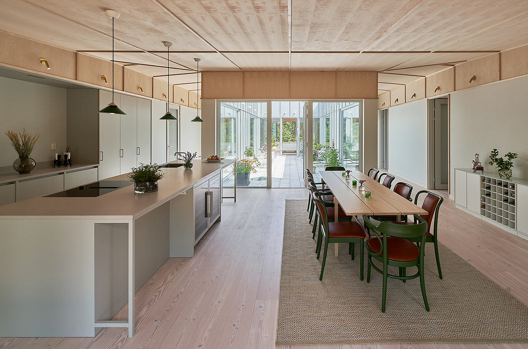 Modern open-plan kitchen and dining area with wood paneling, pendant lights, and large windows.
