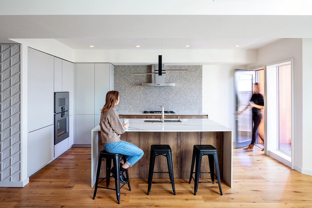 Modern kitchen with sleek cabinetry, stone backsplash, and wooden counter island. Minimalist design.