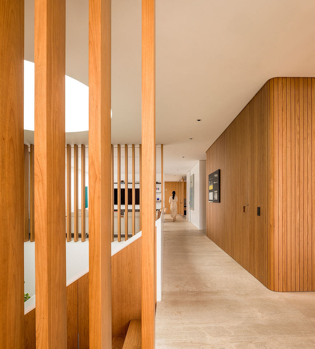 An interior hallway with wooden columns and a long, straight corridor leading to a distant figure.