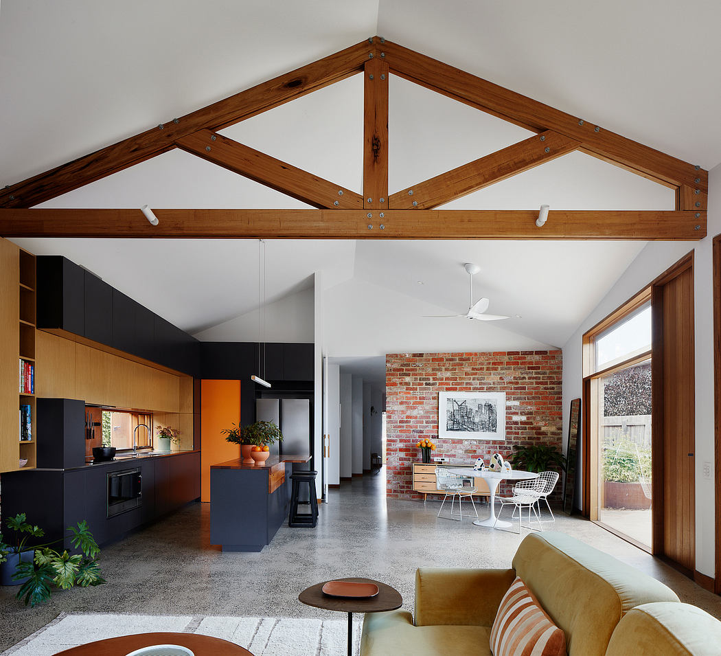 Warm wooden beams frame an open-concept living area with sleek black cabinetry and exposed brick.