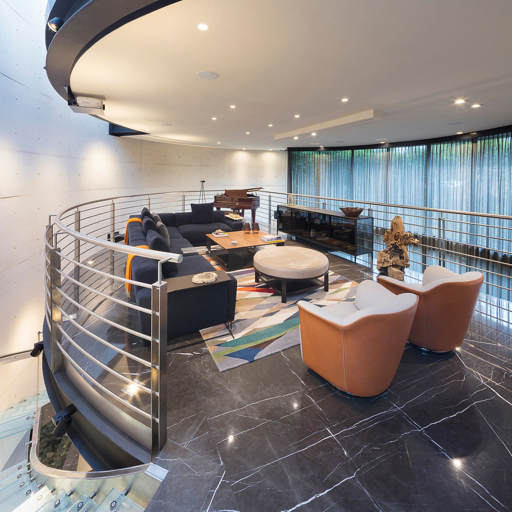 Circular living room with spiral staircase, contemporary furniture, and marble flooring.