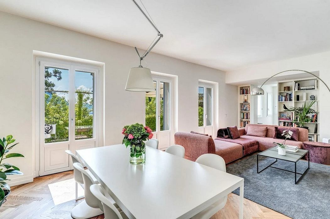 Bright and airy living room with modern furniture, large windows, and lush greenery outside.