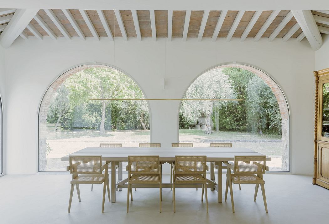 Spacious interior with arched windows, wooden beams, and a modern dining table set.