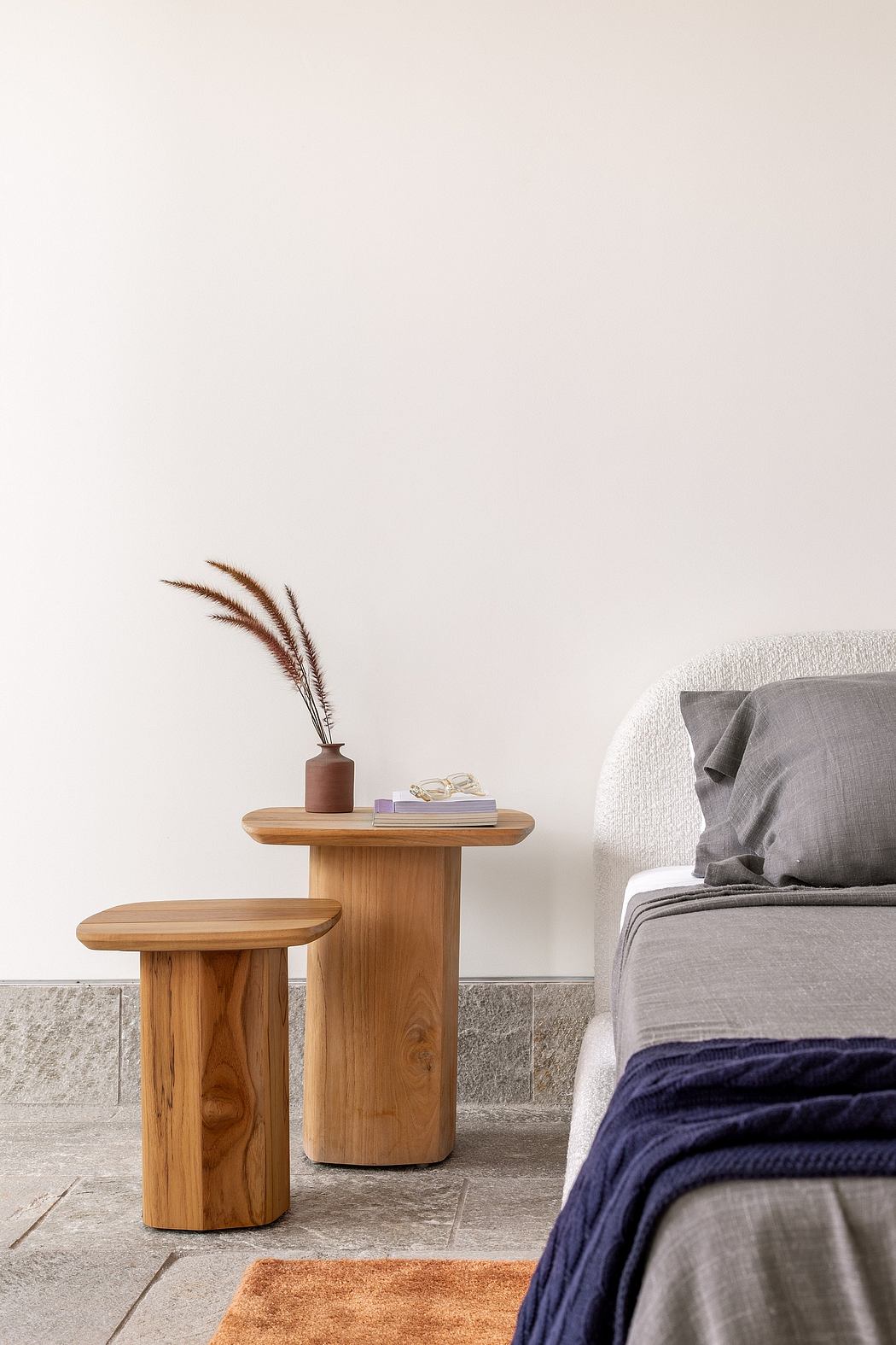 Minimalist bedroom with wooden side tables, gray linens, and textured accents.