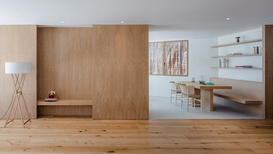 Minimalist interior with natural wood paneling, open shelving, and a wooden dining table.