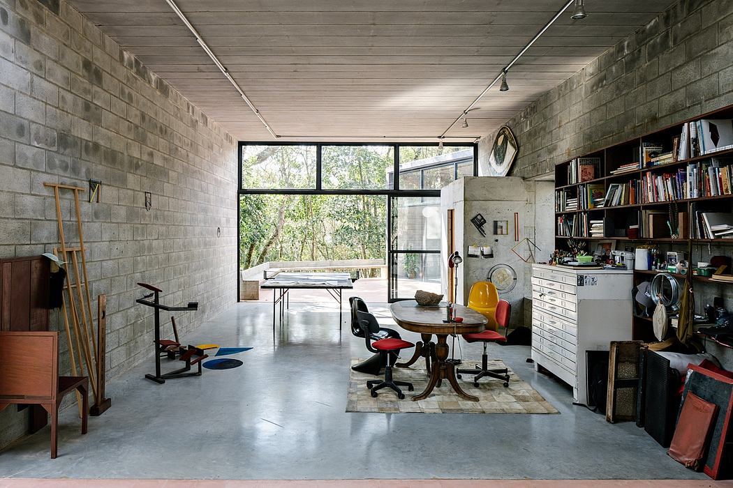 Spacious studio-like interior with concrete walls, large windows, and eclectic furnishings.