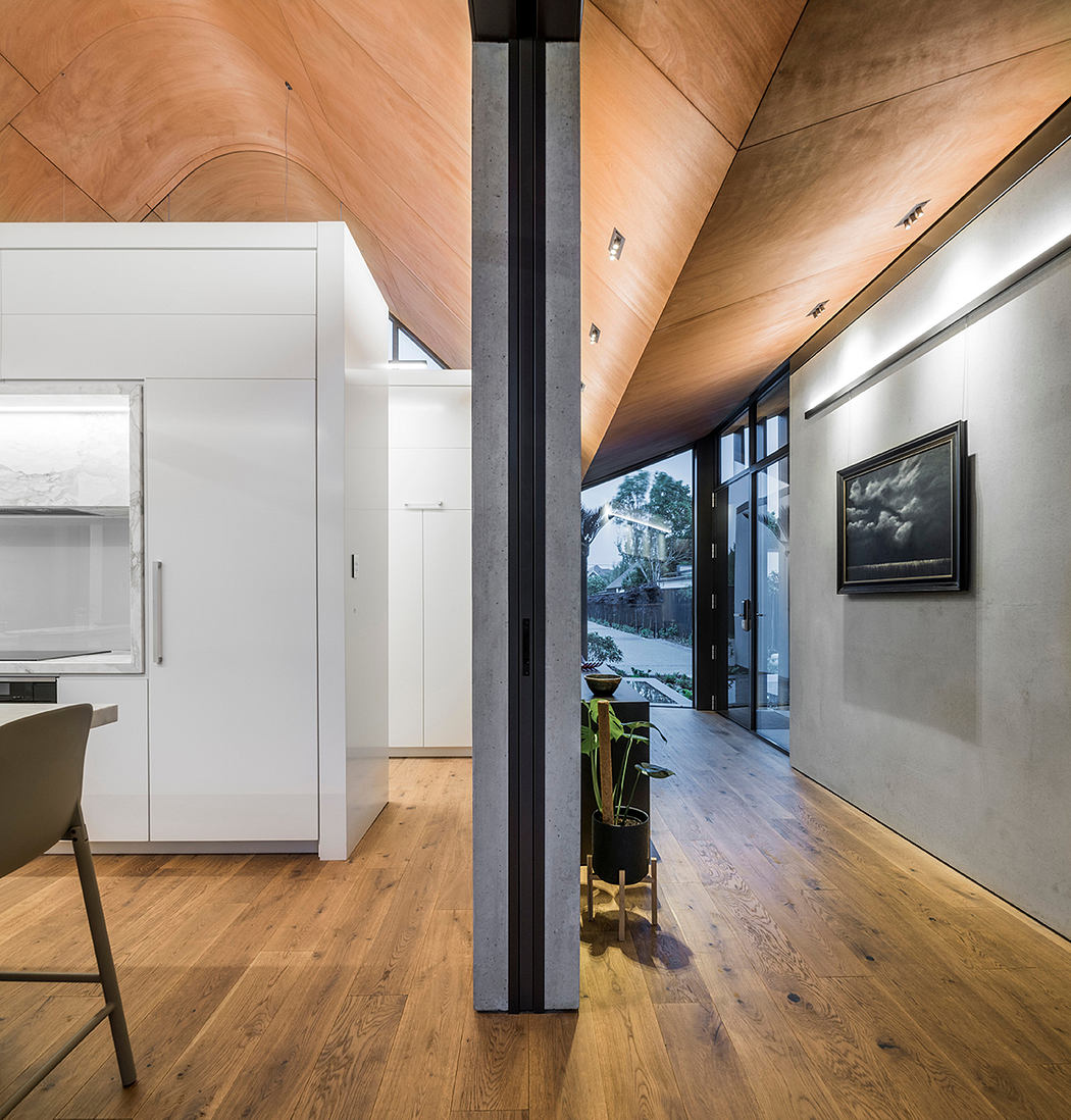 Warm wooden ceiling, sleek white cabinets, and a striking black frame encasing the outdoor view.