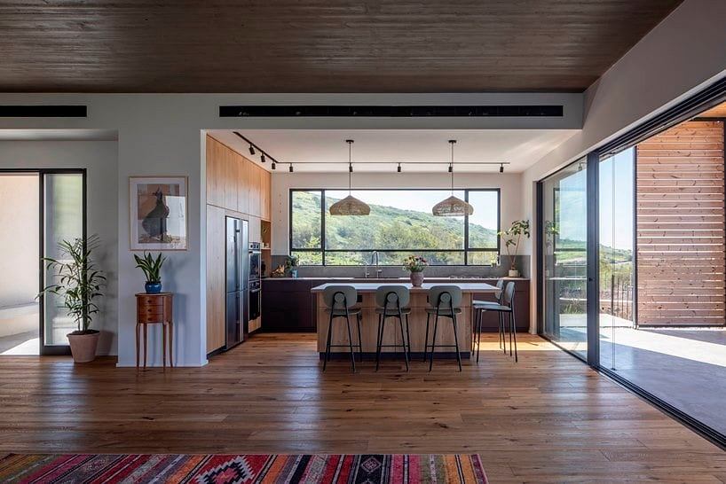Spacious open-plan kitchen and dining area with wood-paneled ceiling, large windows, and eclectic decor.