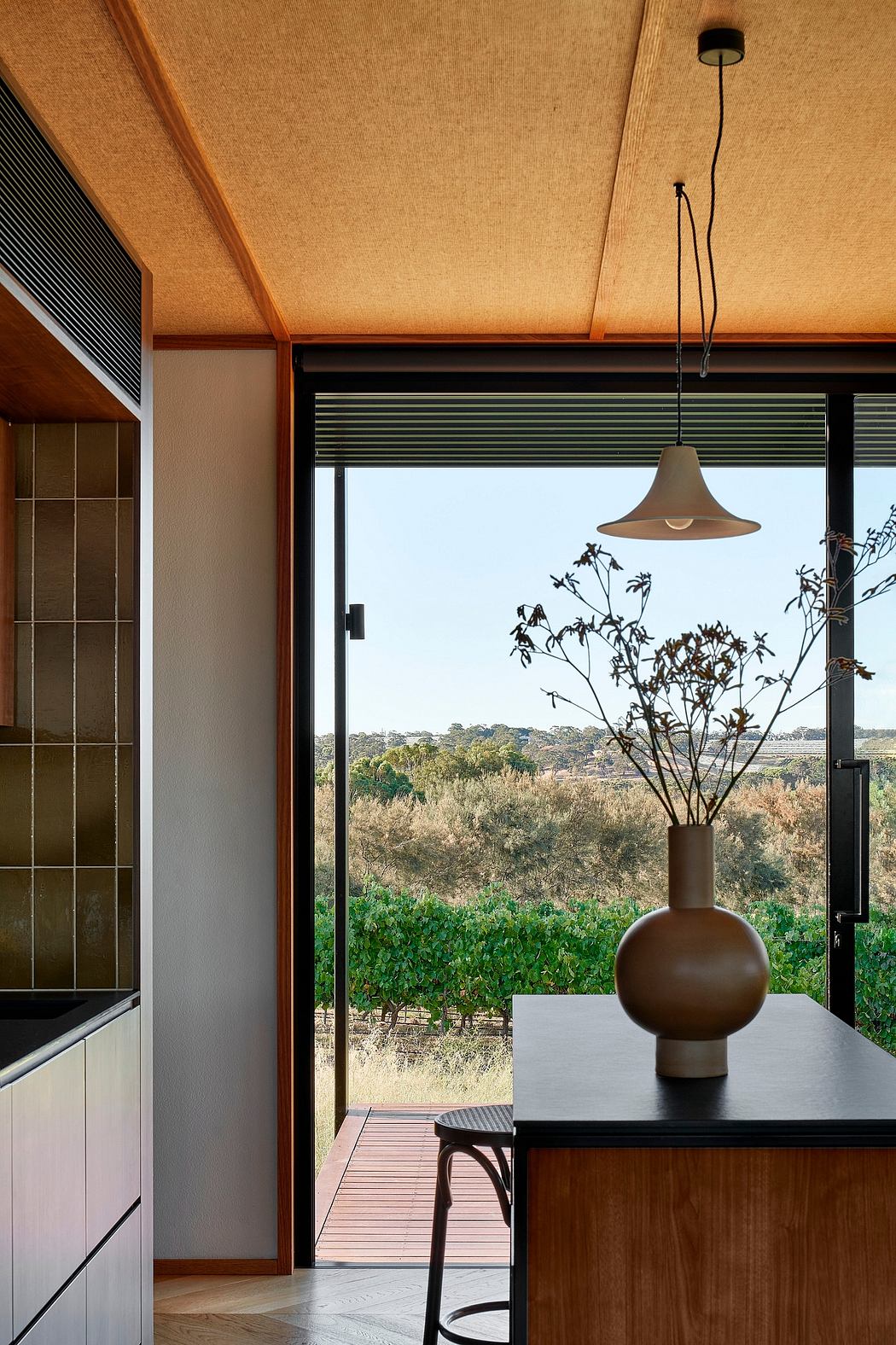 Warm-toned modern interior with large window overlooking lush landscape view.