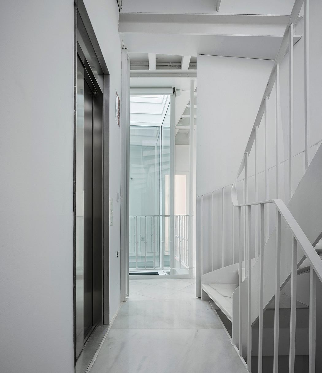 Modern, minimalist interior with glass walls, metal railings, and white tones.