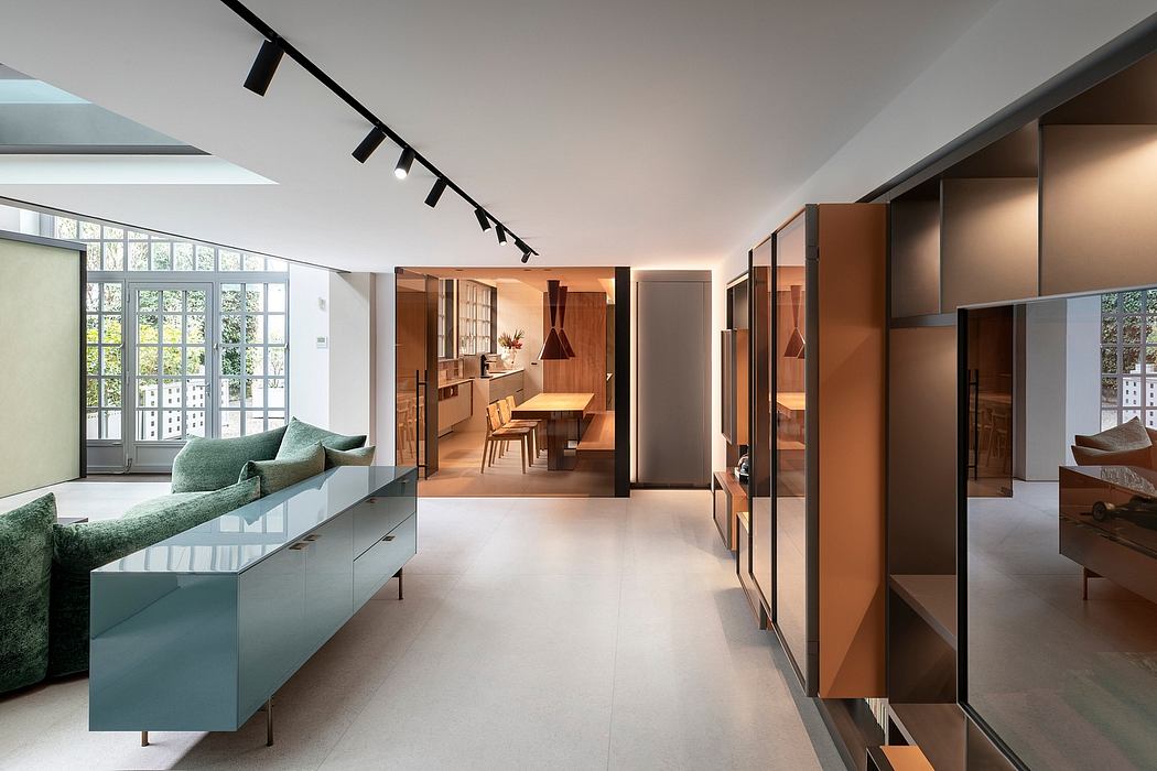 Contemporary open-plan interior with wood and glass furnishings, track lighting, and large windows.