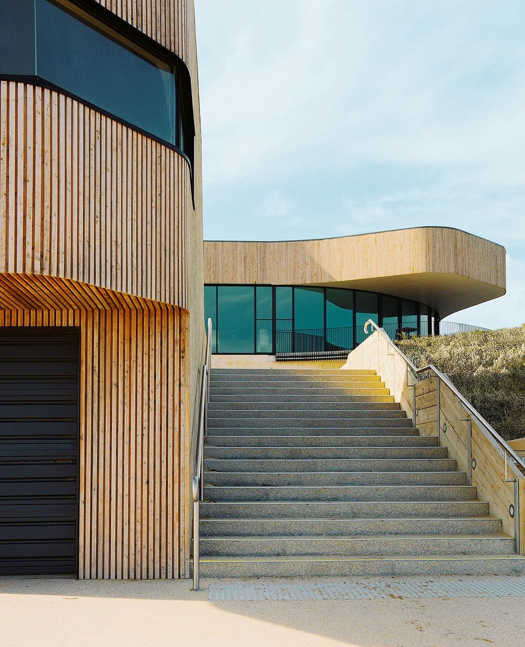 Striking modern building with wooden facades, bold geometric shapes, and a sweeping staircase.