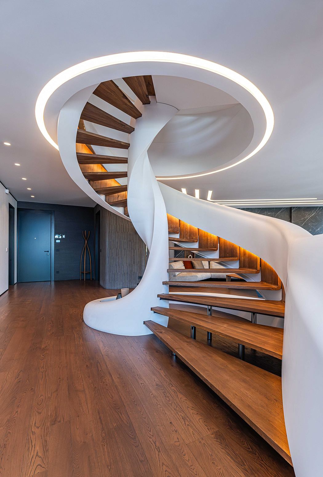 A modern, spiral staircase with wood treads and a curved, illuminated handrail.