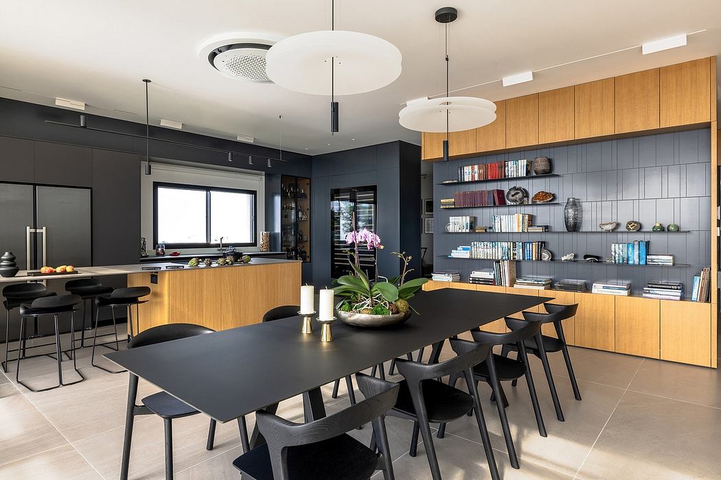 Modern open-concept kitchen and dining area with wooden cabinetry, black furnishings, and suspended lighting.
