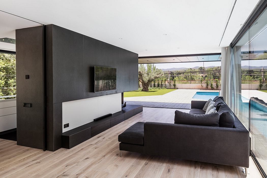 Modern open-plan living room with black accent wall, minimalist furniture, and expansive outdoor view.