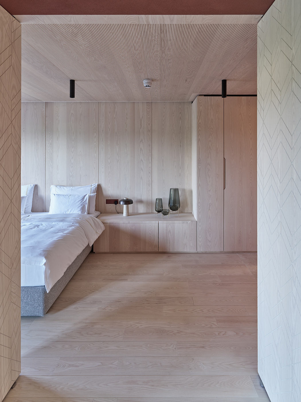 Minimalist bedroom with wood paneled walls, built-in storage, and neutral tones.
