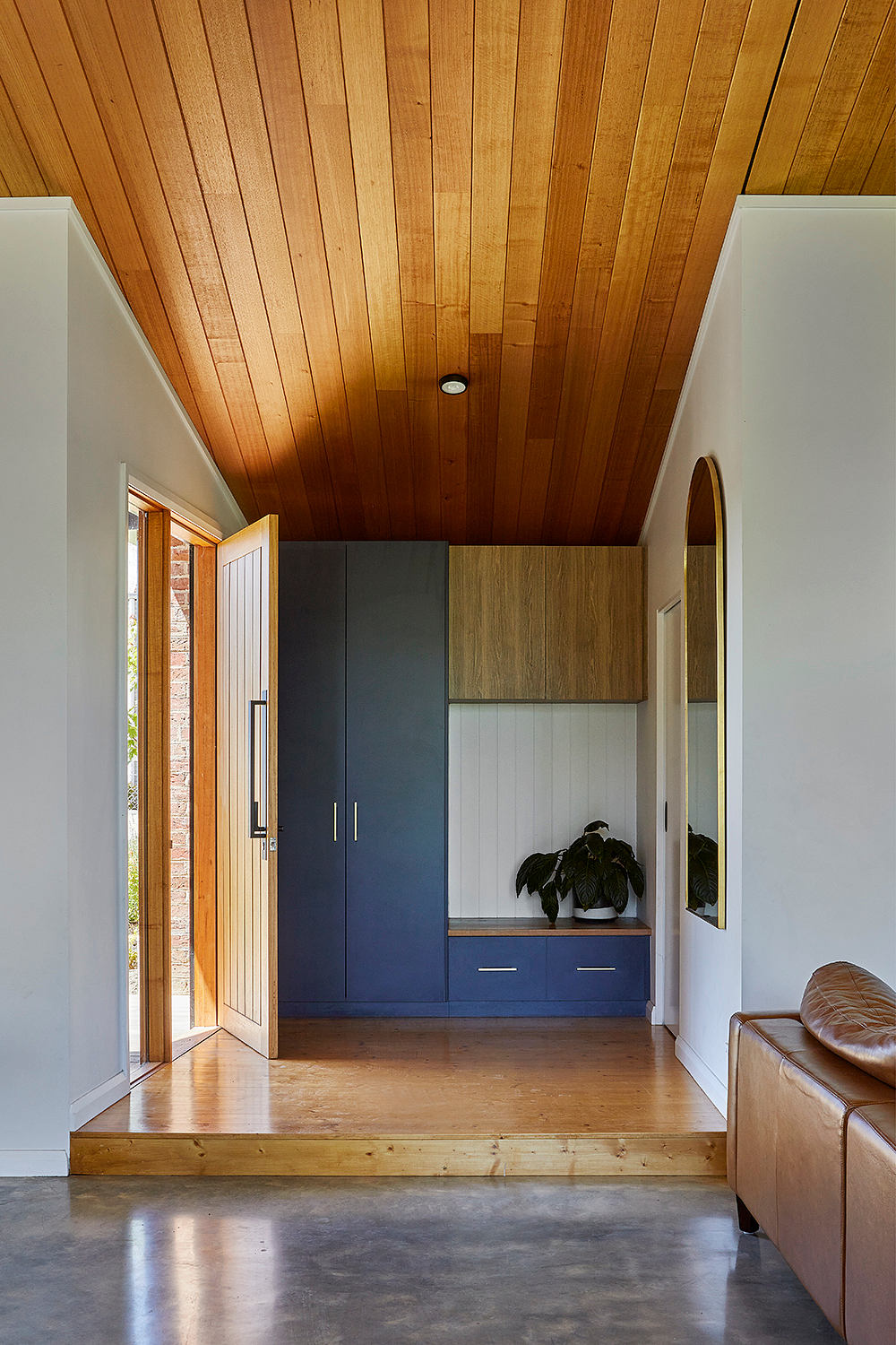 Wooden-planked ceiling, modern blue cabinetry, and a leather couch in the entryway.