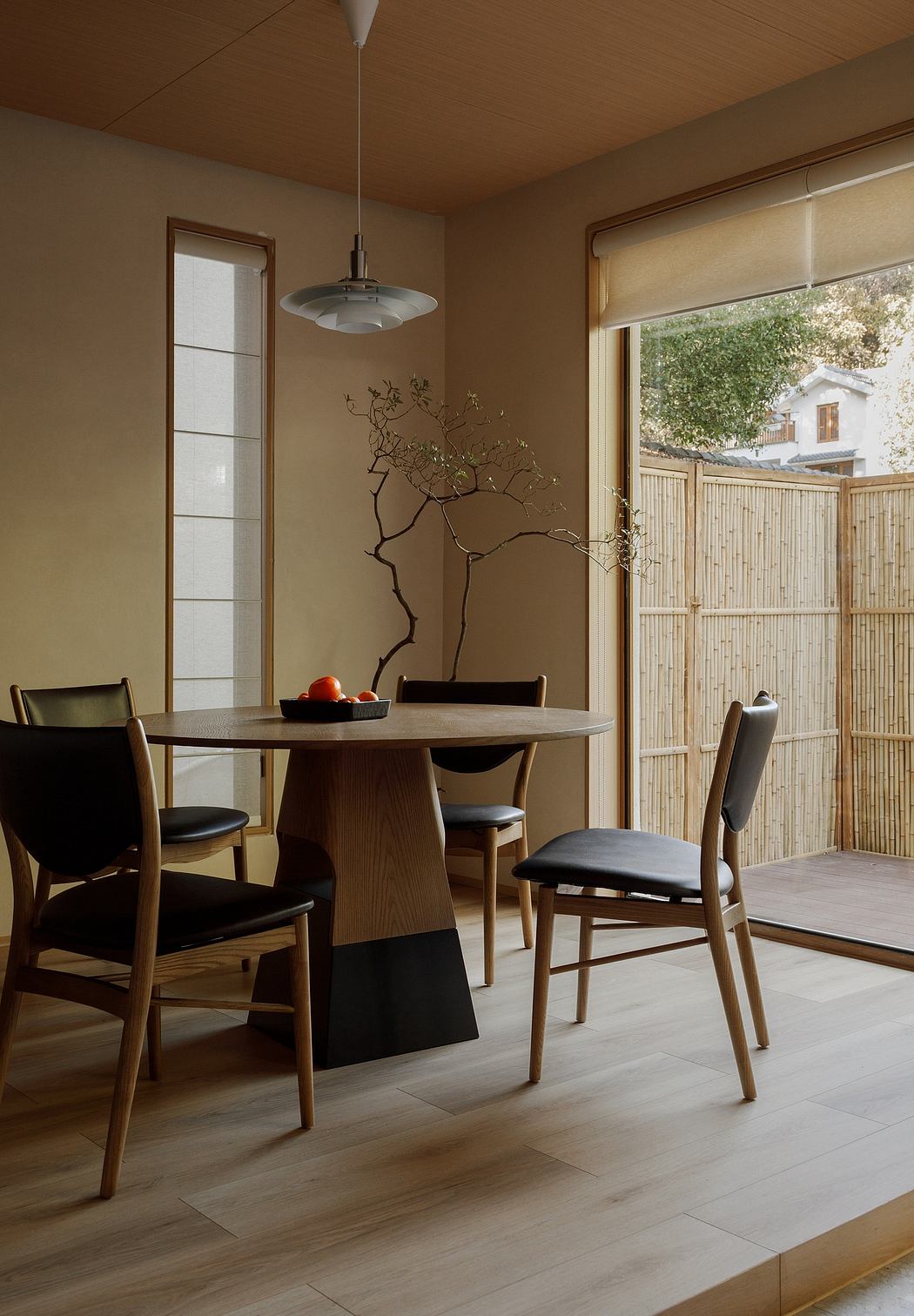 A cozy dining room with a sleek wooden table, chairs, and a decorative tree sculpture.