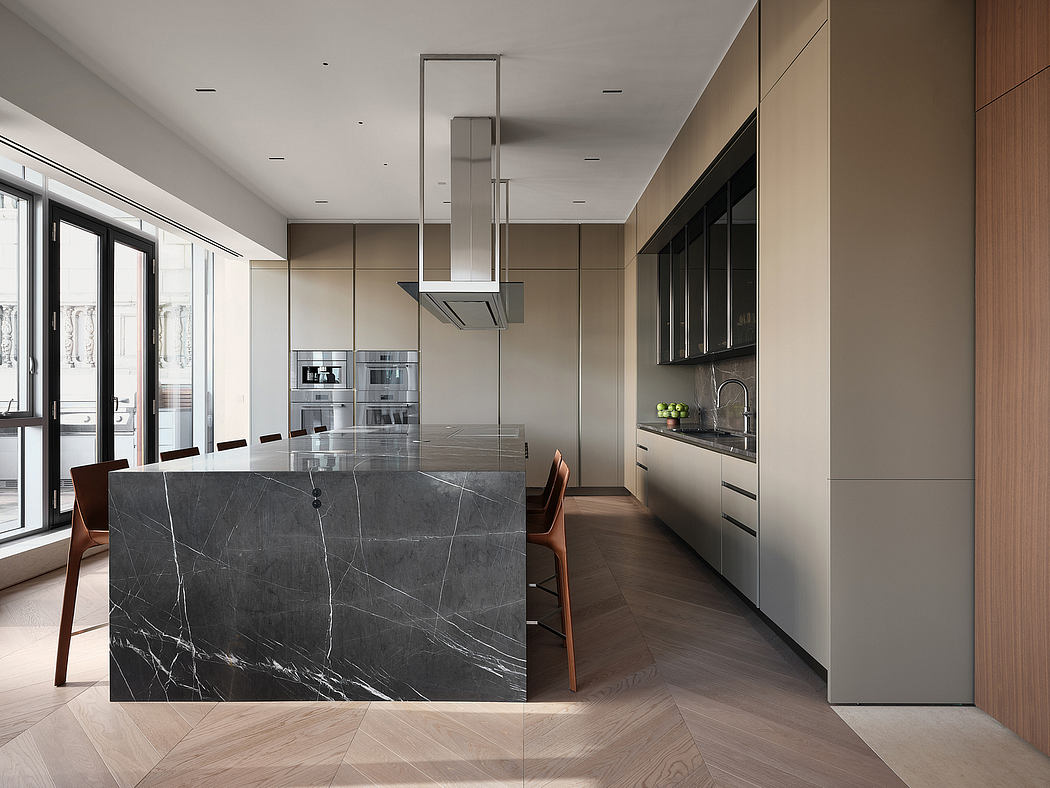 Sleek minimalist kitchen with black marble island, integrated appliances, and wooden flooring.