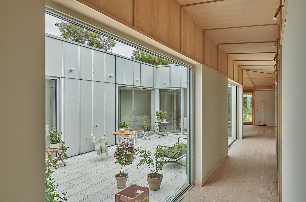 Modern glass-walled interior with wooden paneling, potted plants, and tile flooring.