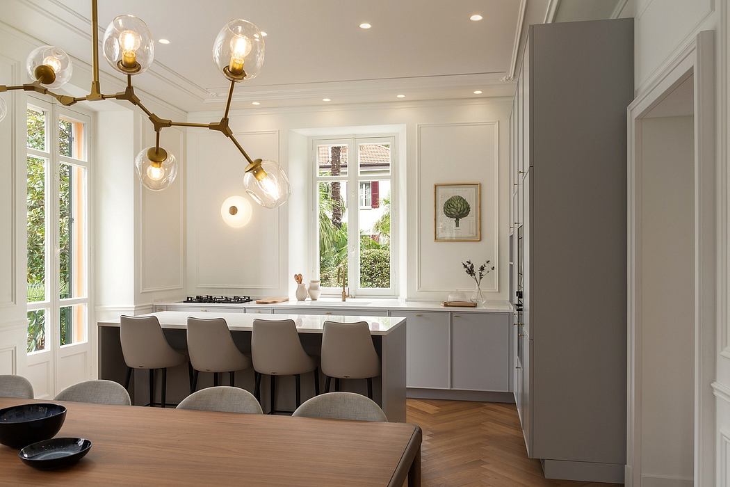 Bright, open kitchen with modern lighting, neutral tones, and expansive windows.
