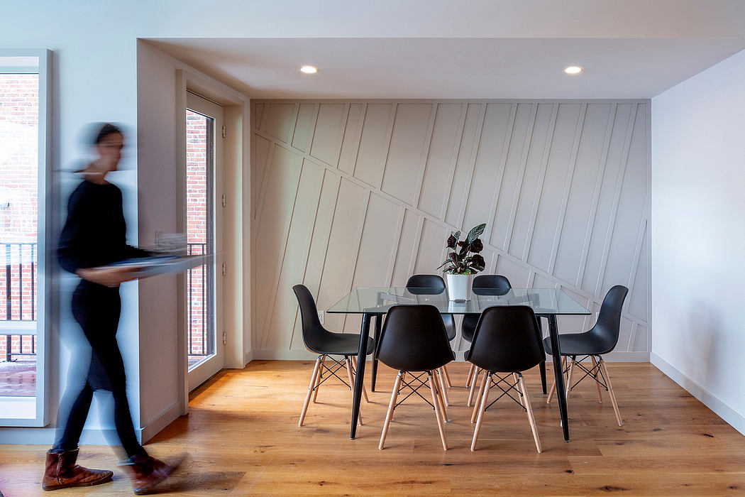 Modern dining room with minimalist furniture, wood floors, and textured wall paneling.