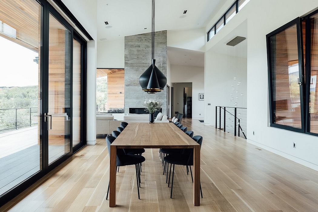 Expansive modern dining area with wood, concrete, and large windows offering scenic views.