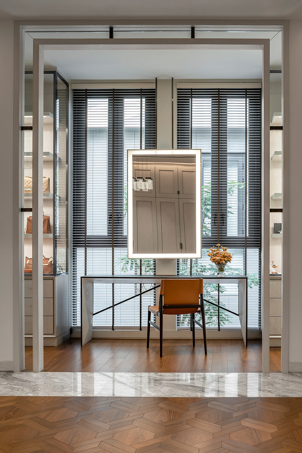 A modern interior featuring sleek framed openings, a wooden console, and a leather chair.