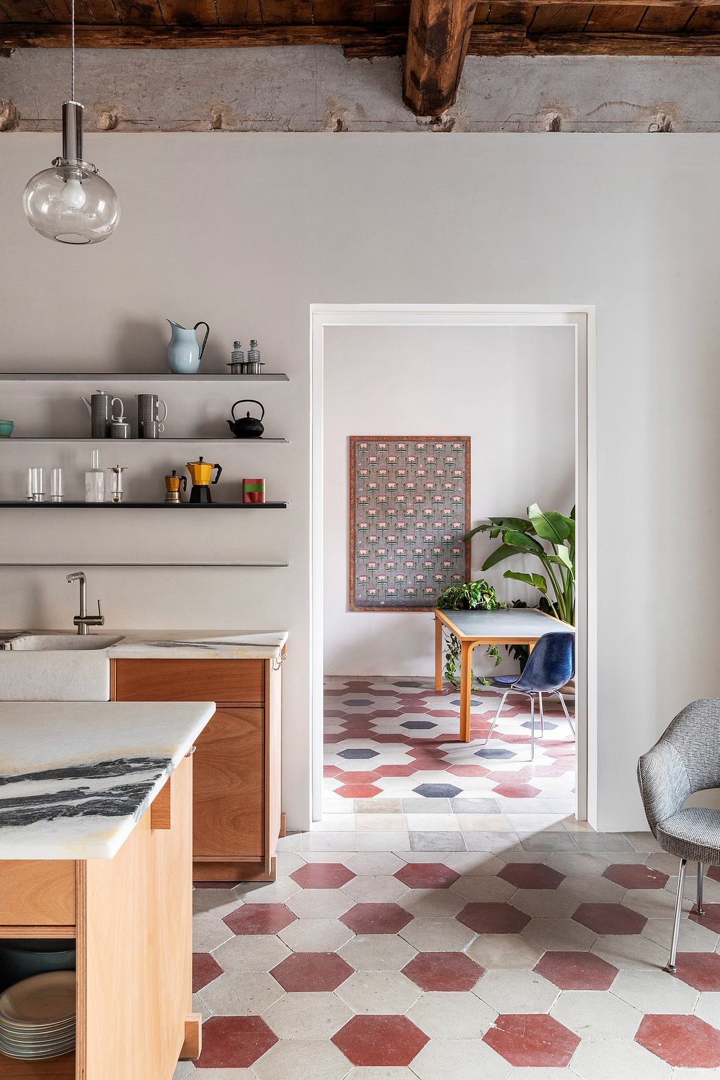A modern, rustic kitchen with hexagonal tile flooring, wooden shelves, and a framed artwork.