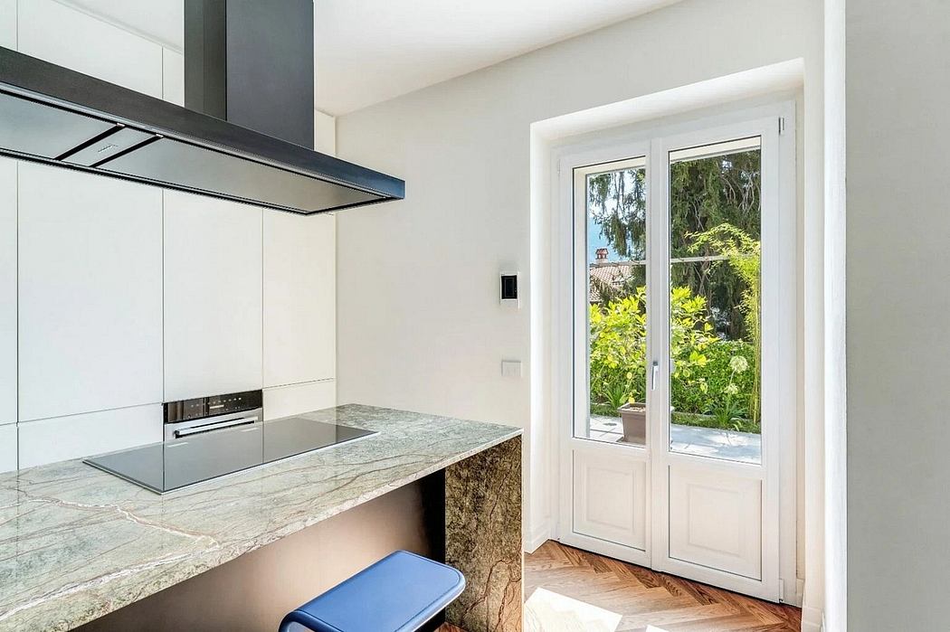 Modern kitchen with sleek appliances, granite countertops, and a glass door leading to the garden.