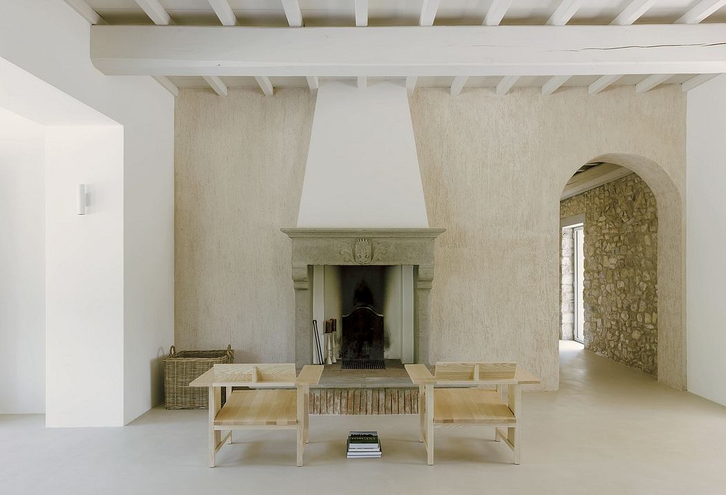 A minimalist living room with a stone fireplace, wooden beams, and simple furniture.