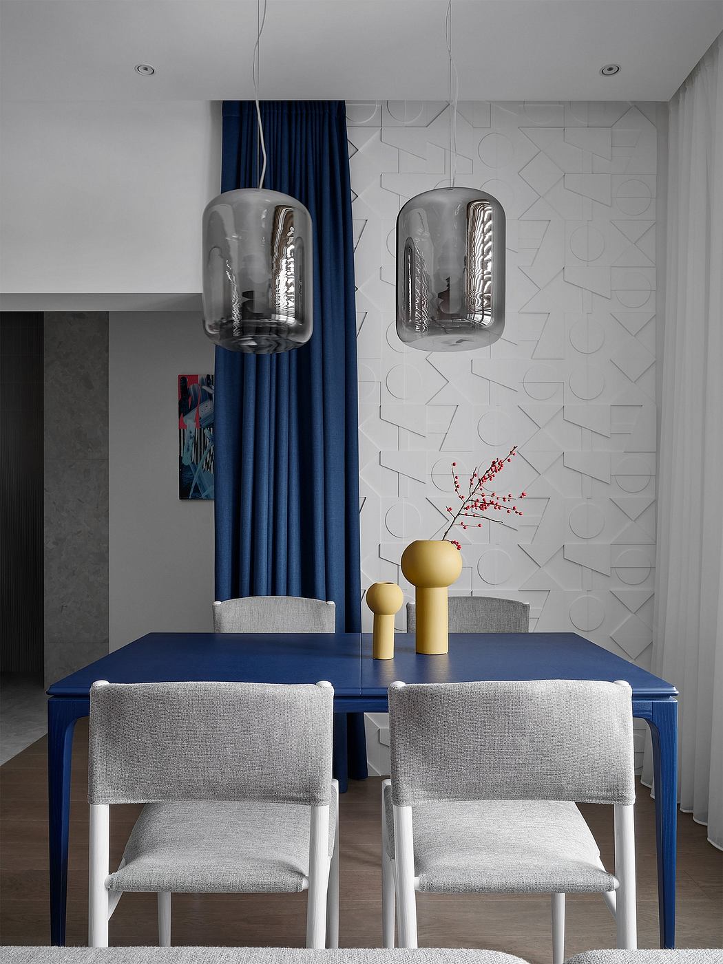 Minimalist dining room with modern pendant lights, geometric wall pattern, and blue table.