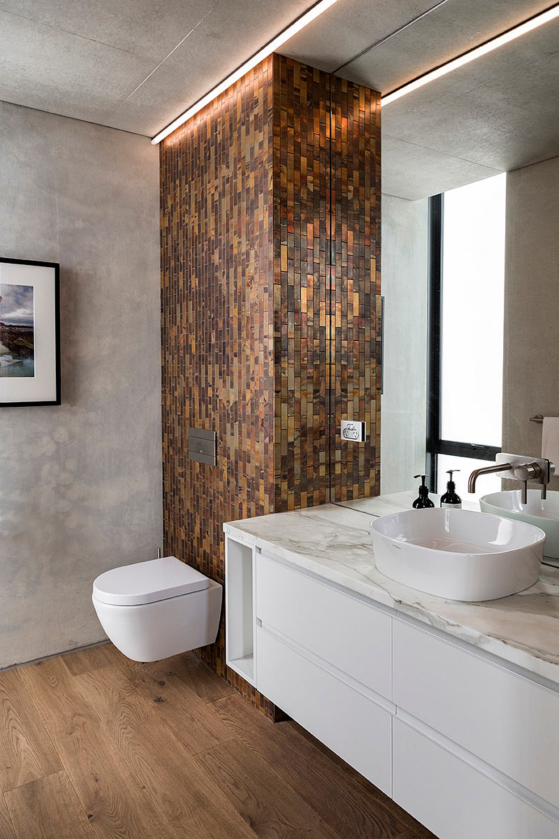 A modern bathroom with a striking feature wall made of wood mosaic tiles and a marble vanity.