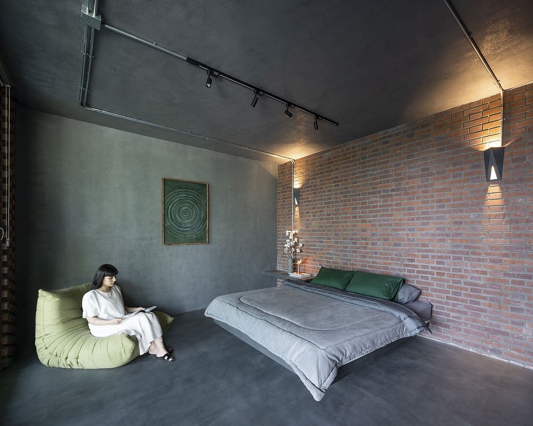 Cozy bedroom with exposed brick wall, plush seating, and minimalist lighting fixtures.