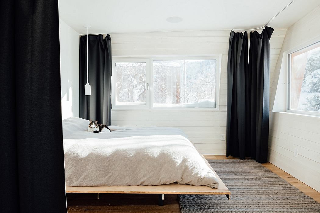 Minimalist bedroom with paned windows, wood platform bed, and monochromatic curtains.