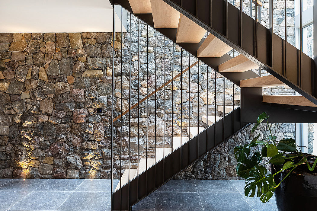 Spacious interior with stone wall, wooden staircase, and glass railing design.