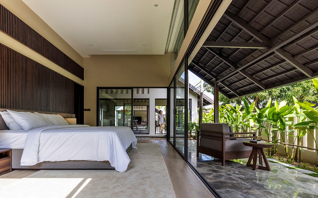 Spacious bedroom with floor-to-ceiling glass doors, tropical vegetation.
