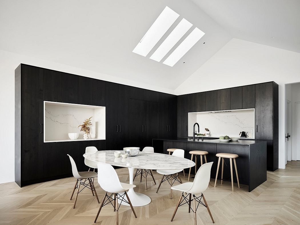 Modern kitchen and dining area with sleek black cabinetry, marble countertops, and ample natural lighting.
