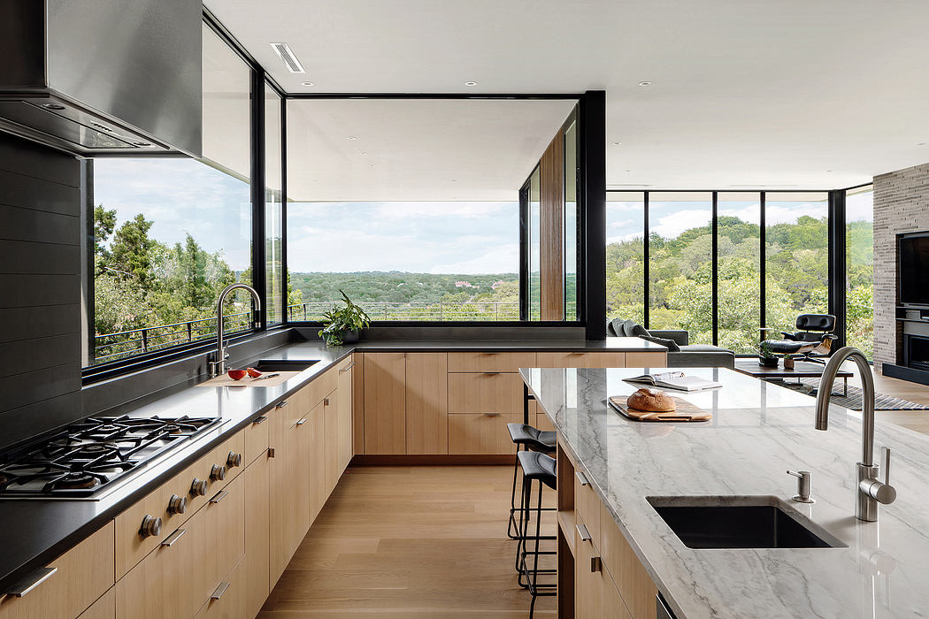 Sleek modern kitchen with expansive windows overlooking lush greenery outside.