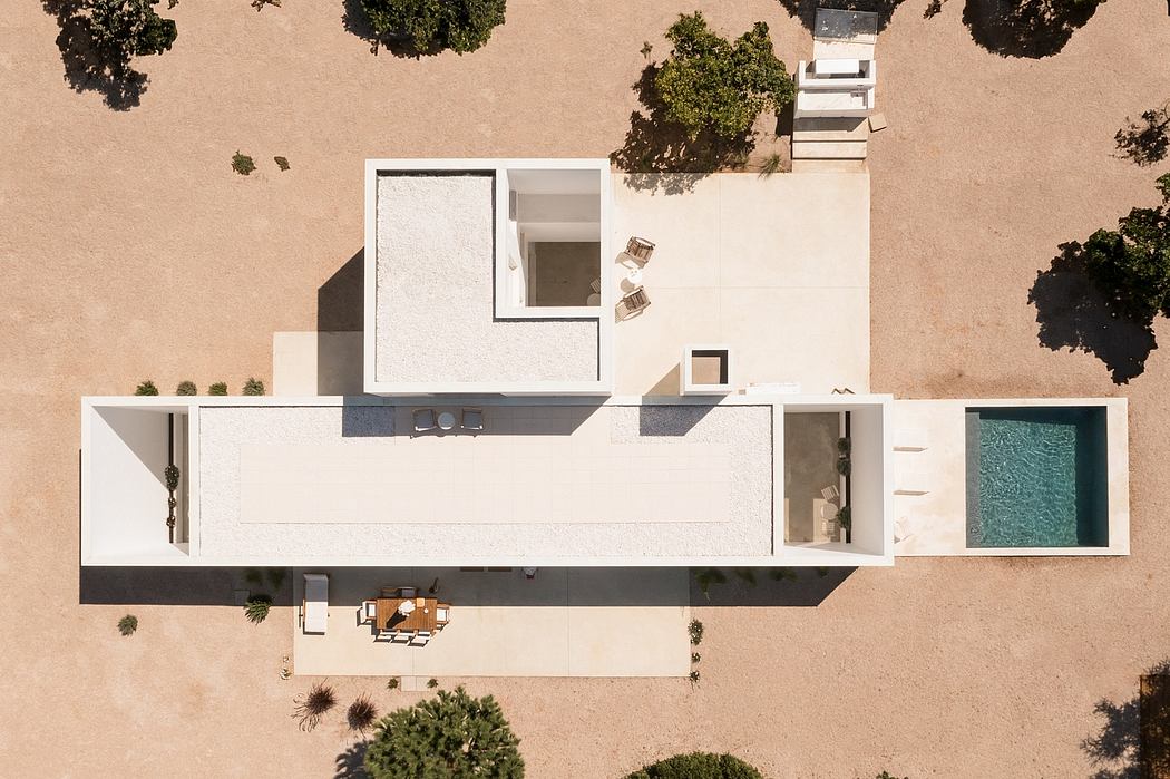 Minimalist, geometric white home with recessed balcony, pool, and landscaping.