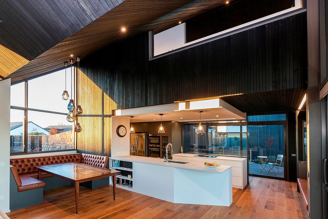 A modern, open-concept kitchen and dining area with wood-paneled walls and pendant lighting.