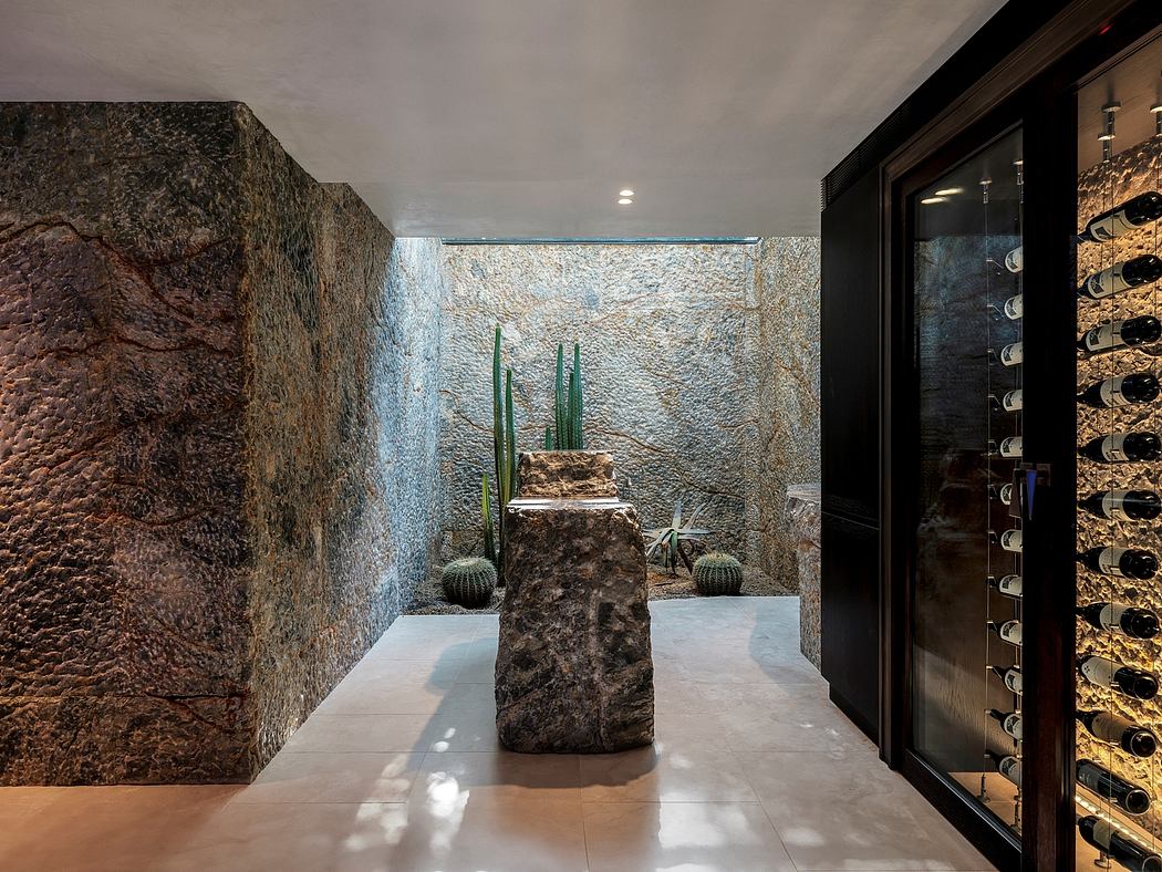 Sleek modern interior with textured stone walls, cacti sculptures, and wine storage.