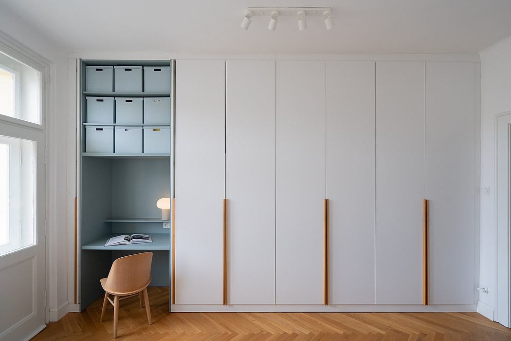 Minimalist room with built-in cabinet, desk, and wooden chair against white walls.
