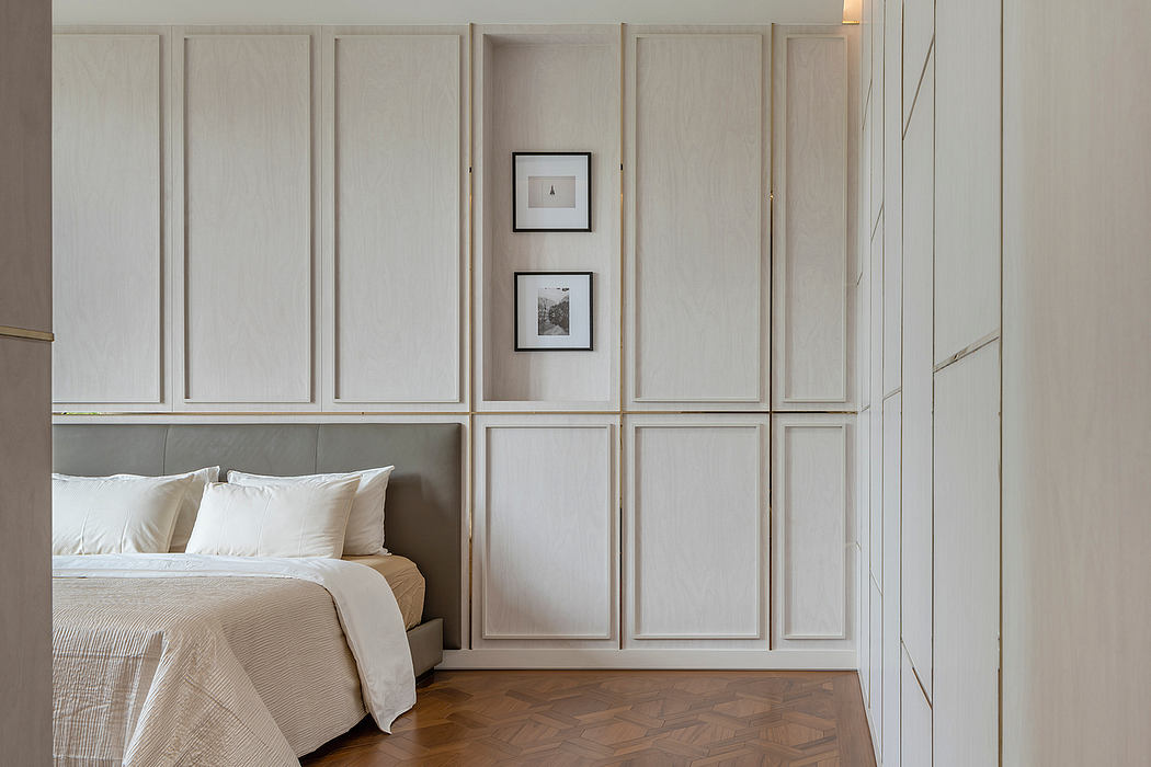 A serene bedroom with paneled walls, framed artwork, and a plush, neutral-toned bed.