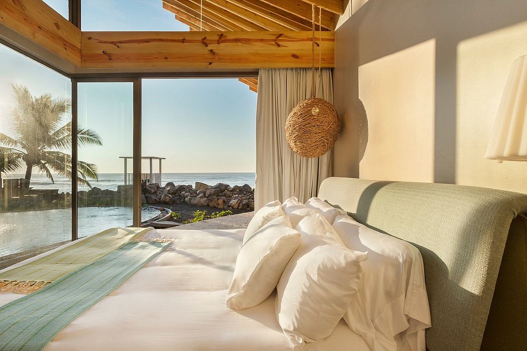 Luxurious coastal bedroom with wooden beams, curtains, and ocean view through large windows.