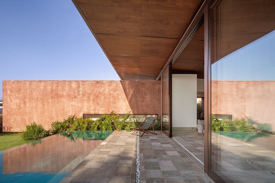 A modern home with a wooden overhang, pool, and lush landscaping against a blue sky.